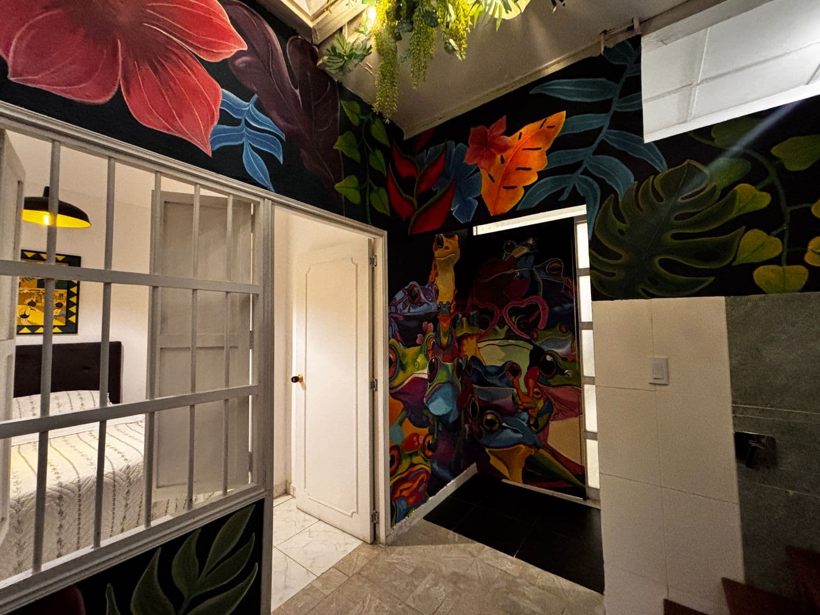 Corredor con murales tropicales en suite Lienzo Hostel